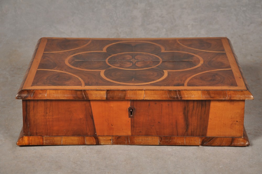 A rectangular 17th-century olive wood lace box featuring geometric oyster veneer marquetry on the lid and a brass keyhole escutcheon on the front.