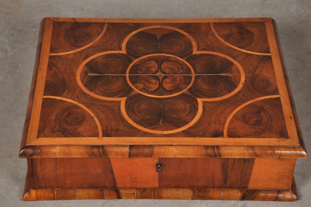 A rectangular 17th-century olive wood lace box featuring geometric oyster veneer marquetry on the lid and a brass keyhole escutcheon on the front. View II
