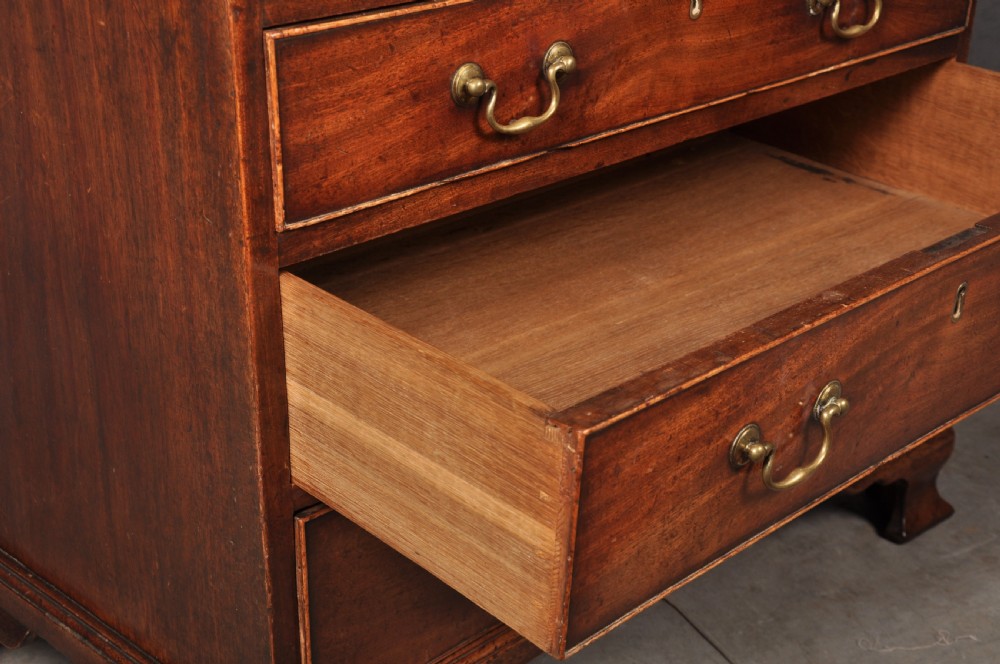 An 18th-century Georgian mahogany chest of drawers featuring four graduated drawers, brass swan-neck handles, a brushing slide, and bracket feet. View IV