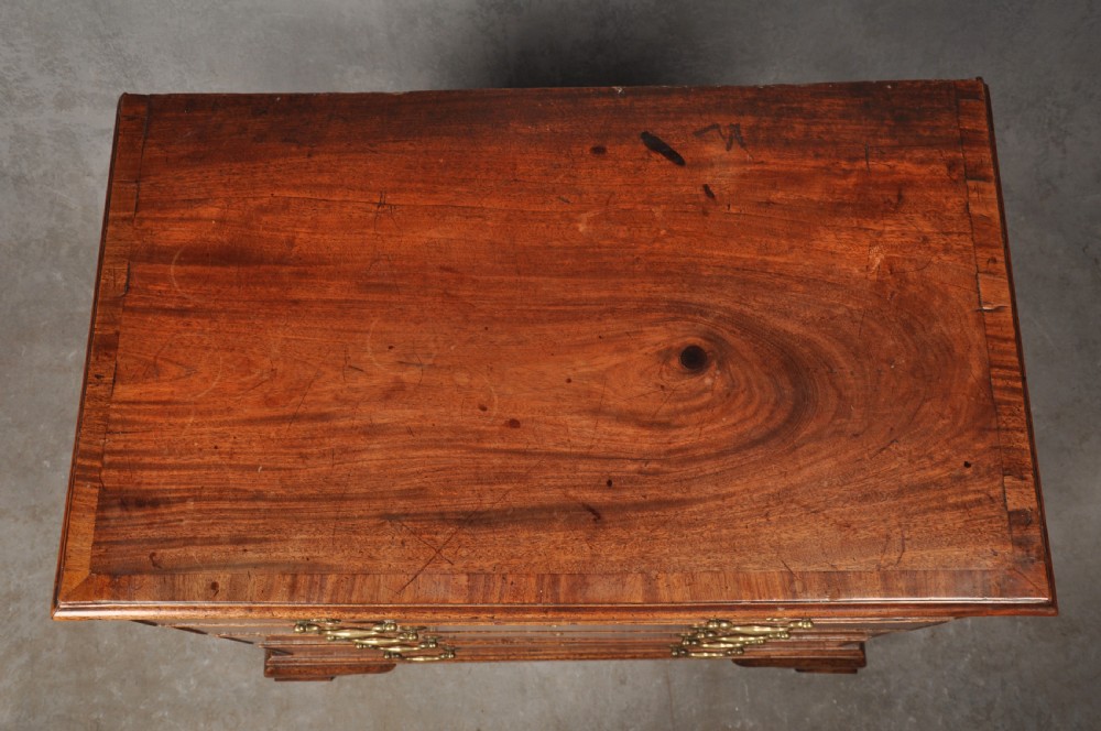 An 18th-century Georgian mahogany chest of drawers featuring four graduated drawers, brass swan-neck handles, a brushing slide, and bracket feet. View V