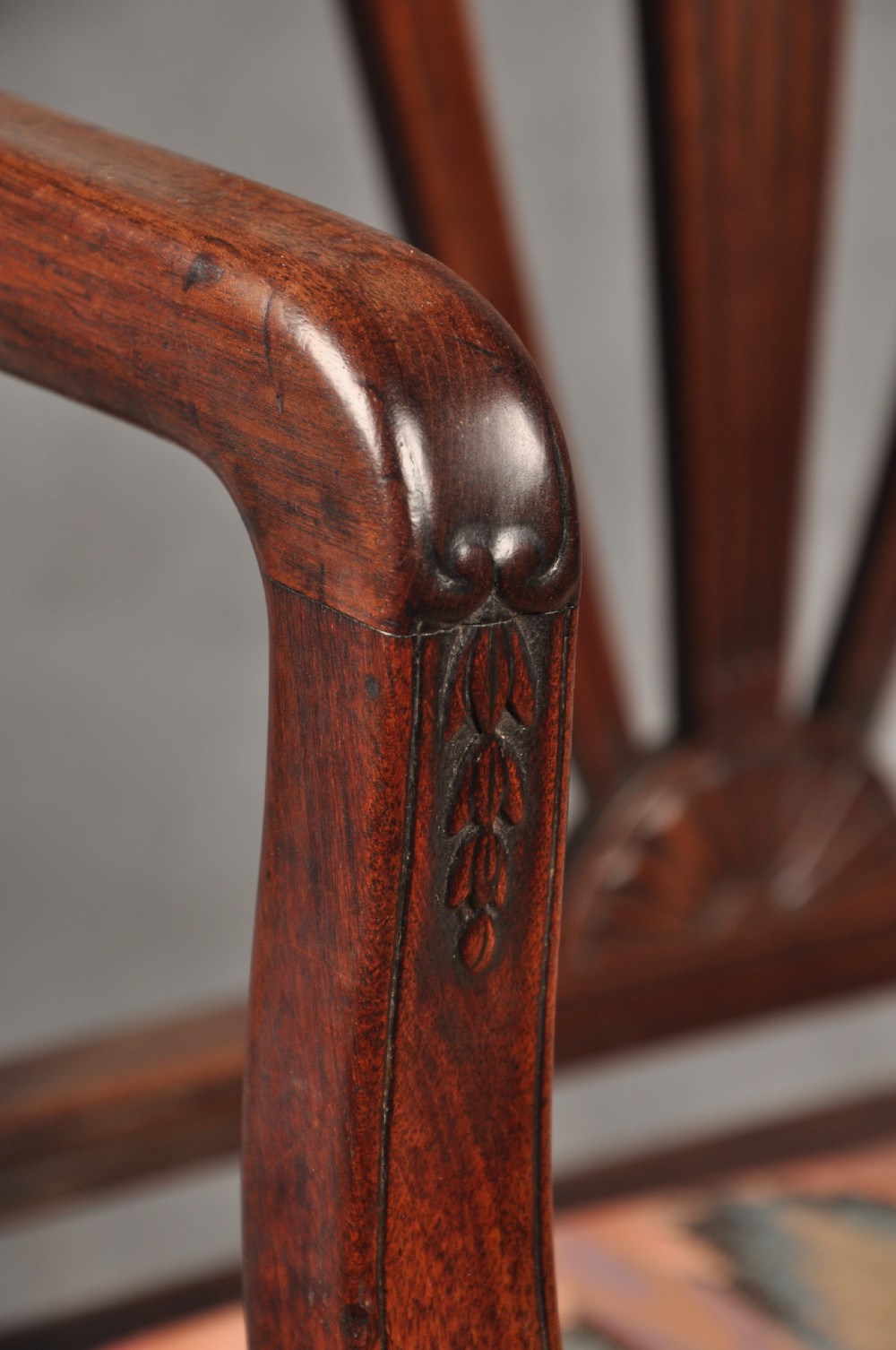 An 18th-century dark mahogany open armchair with a carved back splat, curved arms, square legs with stretchers, and pattern-upholstered seat. View V