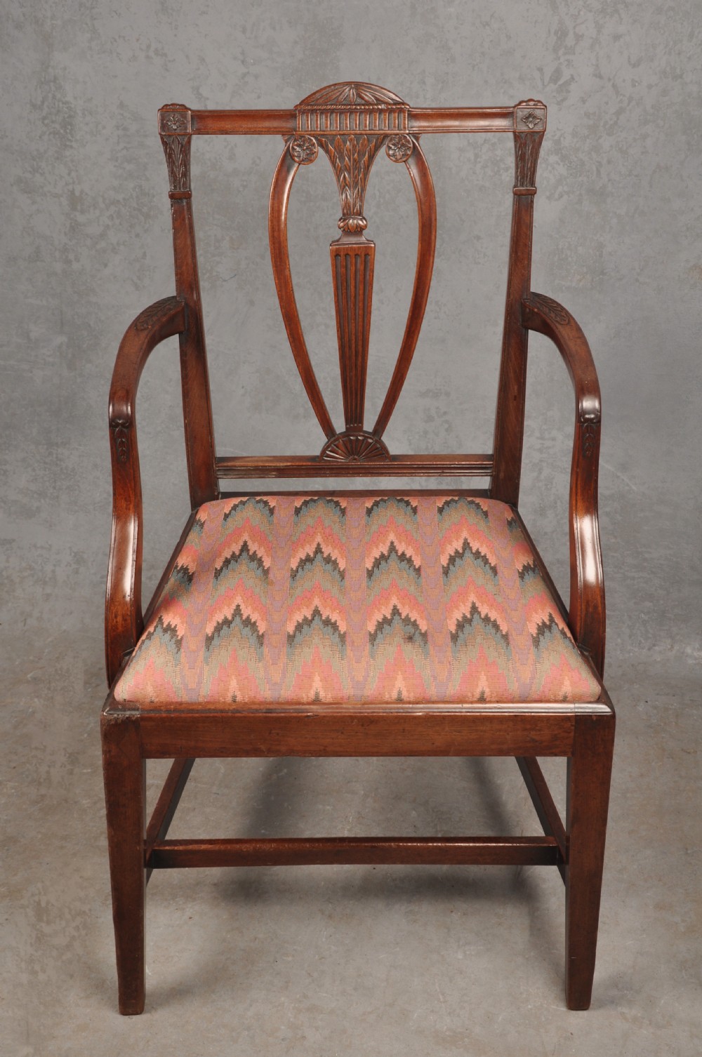 An 18th-century dark mahogany open armchair with a carved back splat, curved arms, square legs with stretchers, and pattern-upholstered seat. View VI