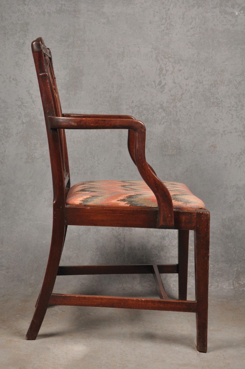 An 18th-century dark mahogany open armchair with a carved back splat, curved arms, square legs with stretchers, and pattern-upholstered seat. View VII