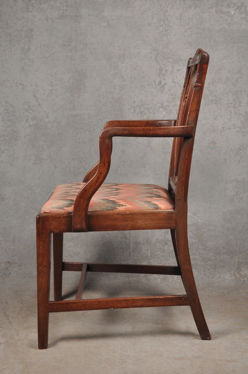 An 18th-century dark mahogany open armchair with a carved back splat, curved arms, square legs with stretchers, and pattern-upholstered seat. View VIII