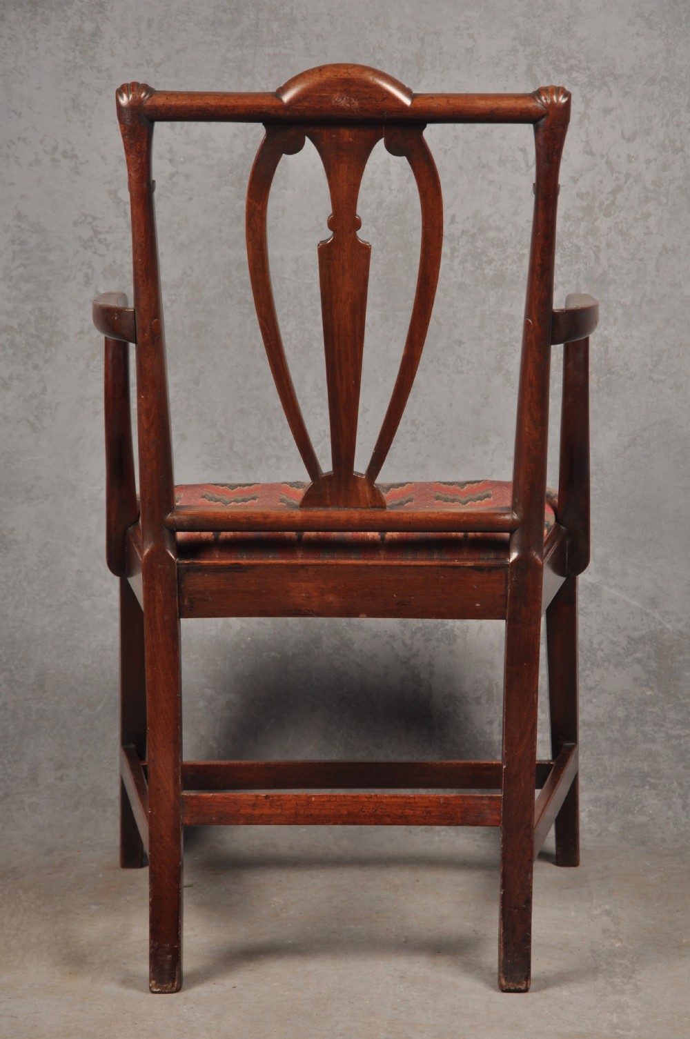 An 18th-century dark mahogany open armchair with a carved back splat, curved arms, square legs with stretchers, and pattern-upholstered seat. View IX
