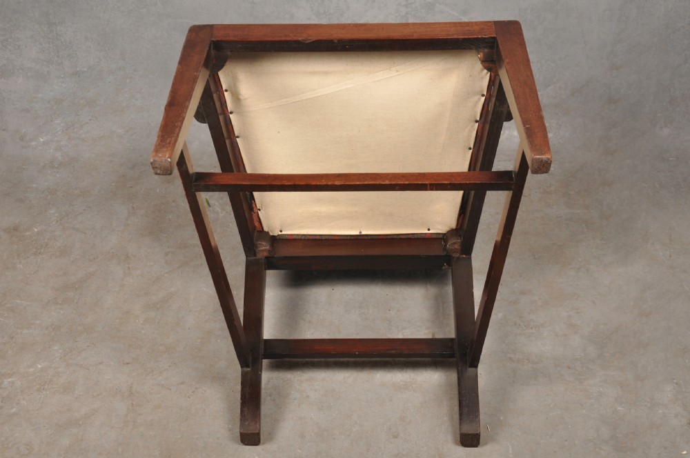 An 18th-century dark mahogany open armchair with a carved back splat, curved arms, square legs with stretchers, and pattern-upholstered seat. View X