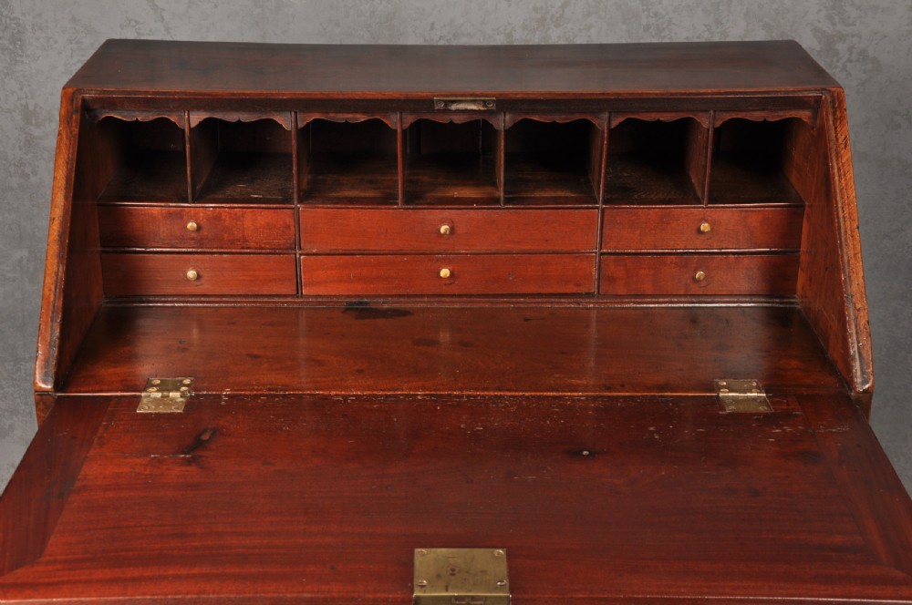 An 18th-century mahogany slant-front writing bureau featuring four graduated drawers with brass handles, standing on bracket feet. View V
