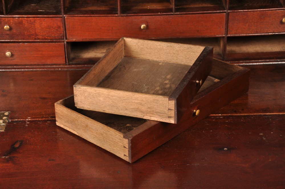 An 18th-century mahogany slant-front writing bureau featuring four graduated drawers with brass handles, standing on bracket feet. View VI