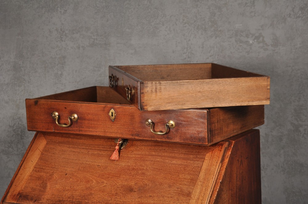 An 18th-century mahogany slant-front writing bureau featuring four graduated drawers with brass handles, standing on bracket feet. View VII