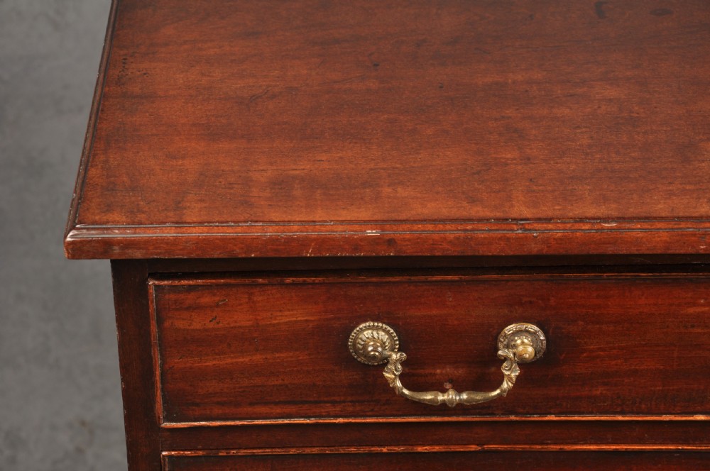 A Georgian mahogany chest featuring four graduated drawers with brass swan-neck handles and bracket feet. View V