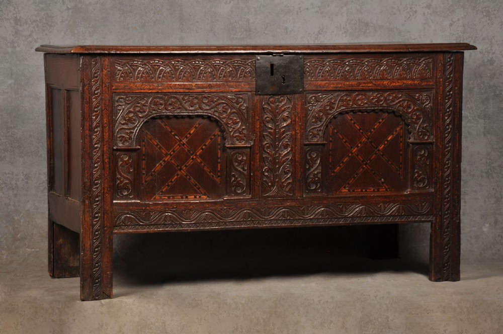 Early 17th-century dark carved oak coffer featuring dual arched panels with geometric inlay and an iron lock plate. View II