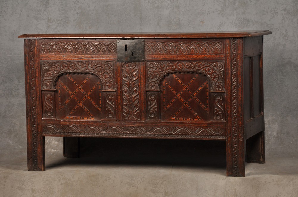Early 17th-century dark carved oak coffer featuring dual arched panels with geometric inlay and an iron lock plate. View III