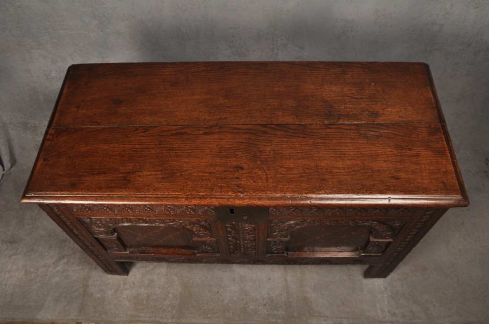 Early 17th-century dark carved oak coffer featuring dual arched panels with geometric inlay and an iron lock plate. View IV