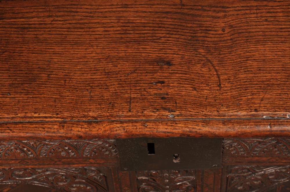 Early 17th-century dark carved oak coffer featuring dual arched panels with geometric inlay and an iron lock plate. View V