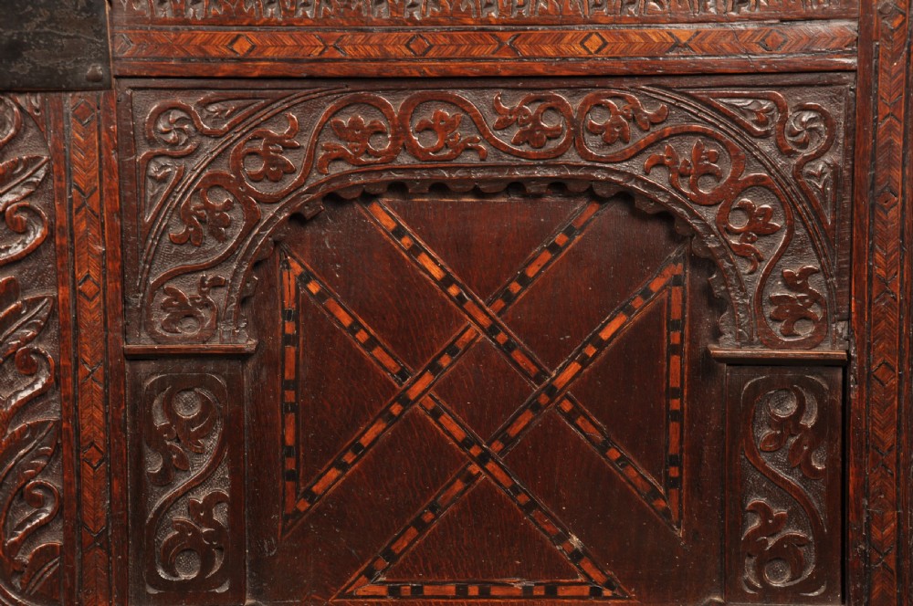 Early 17th-century dark carved oak coffer featuring dual arched panels with geometric inlay and an iron lock plate. View VI