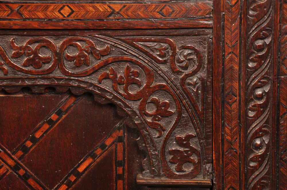 Early 17th-century dark carved oak coffer featuring dual arched panels with geometric inlay and an iron lock plate. View VII