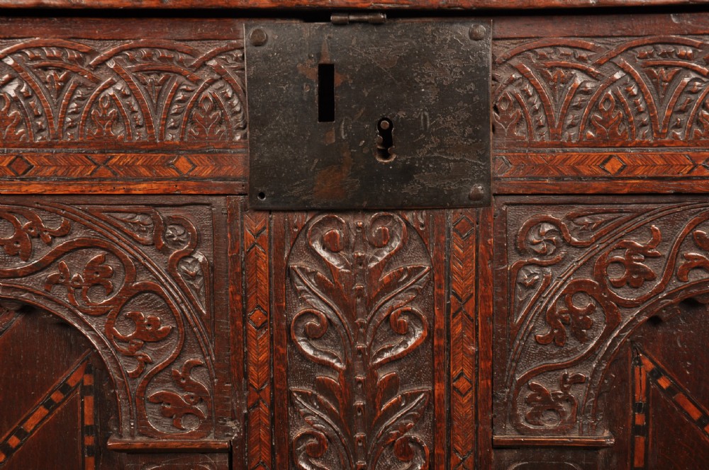 Early 17th-century dark carved oak coffer featuring dual arched panels with geometric inlay and an iron lock plate. View VIII