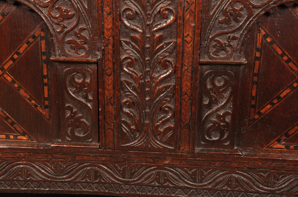 Early 17th-century dark carved oak coffer featuring dual arched panels with geometric inlay and an iron lock plate. View IX