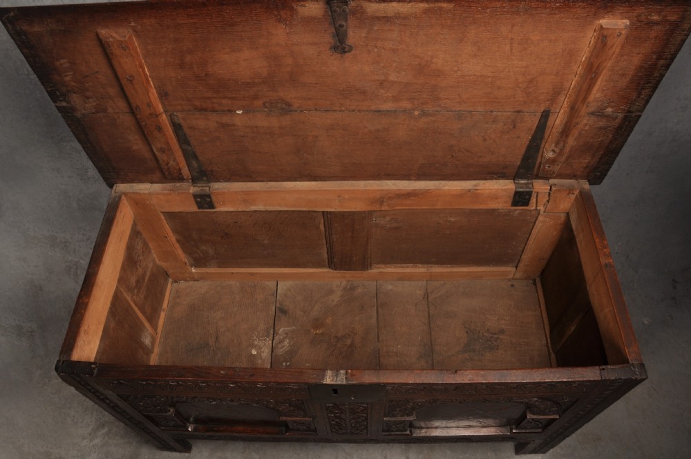 Early 17th-century dark carved oak coffer featuring dual arched panels with geometric inlay and an iron lock plate. View X