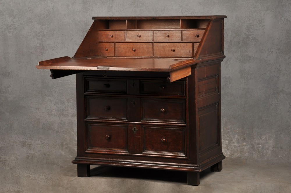 A 17th-century dark oak bureau featuring a sloped drop-down lid, geometric moulded drawers, and iron keyhole escutcheons. View III