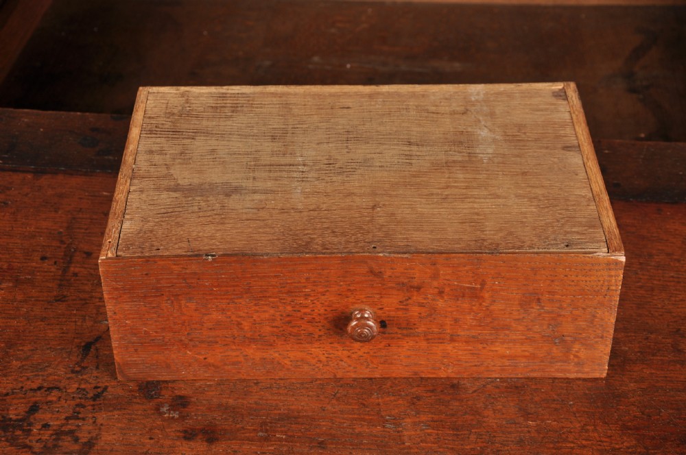 A 17th-century dark oak bureau featuring a sloped drop-down lid, geometric moulded drawers, and iron keyhole escutcheons. View VII