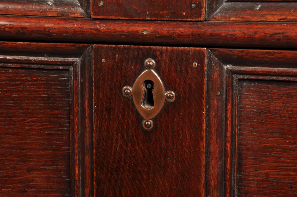 A 17th-century dark oak bureau featuring a sloped drop-down lid, geometric moulded drawers, and iron keyhole escutcheons. View IX