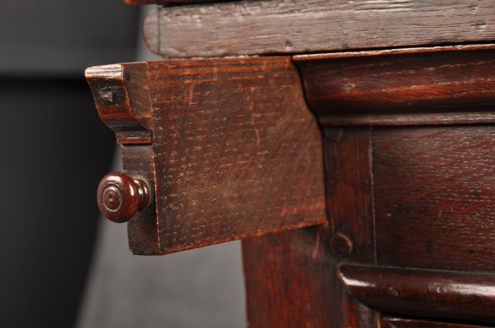 A 17th-century dark oak bureau featuring a sloped drop-down lid, geometric moulded drawers, and iron keyhole escutcheons. View XIII