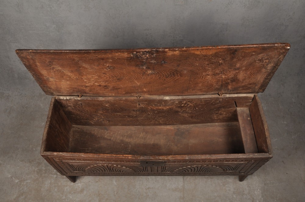 A low 17th-century dark oak coffer with relief carved lunette patterns and a central iron lockplate. View IV