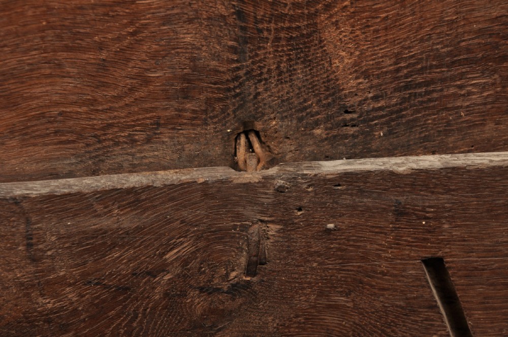 A low 17th-century dark oak coffer with relief carved lunette patterns and a central iron lockplate. View V