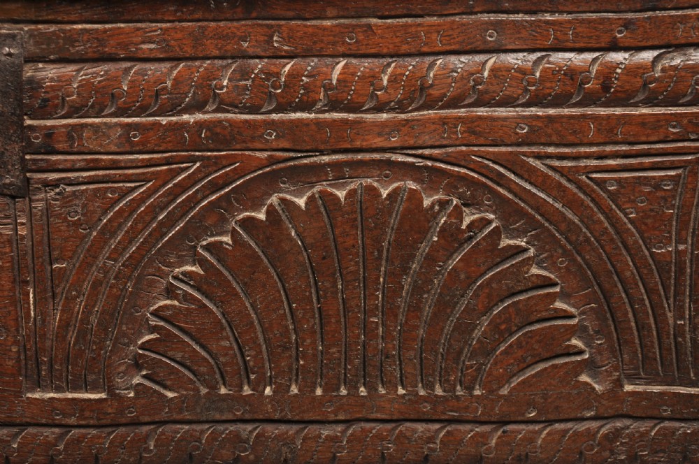 A low 17th-century dark oak coffer with relief carved lunette patterns and a central iron lockplate. View VI