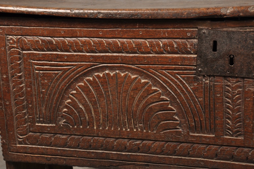 A low 17th-century dark oak coffer with relief carved lunette patterns and a central iron lockplate. View VII