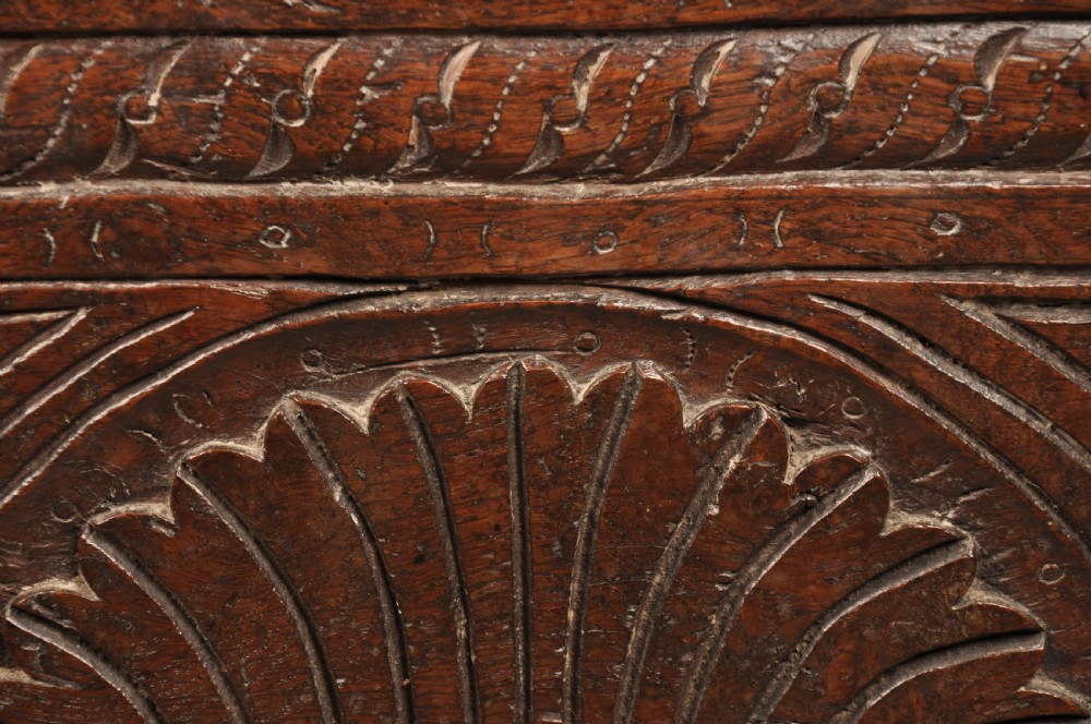 A low 17th-century dark oak coffer with relief carved lunette patterns and a central iron lockplate. View VIII