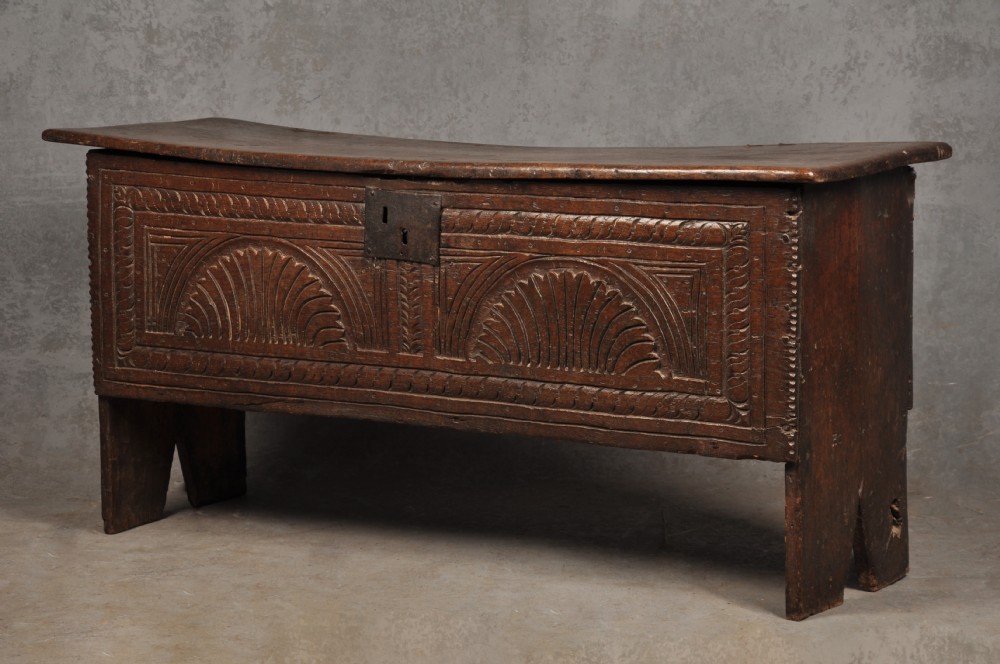 A low 17th-century dark oak coffer with relief carved lunette patterns and a central iron lockplate. View III
