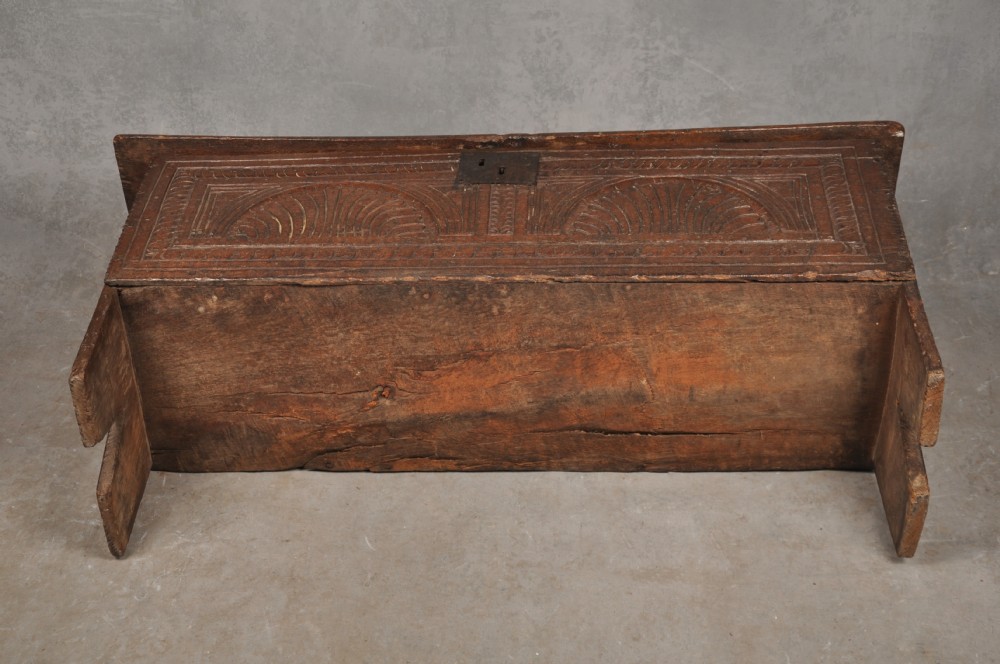 A low 17th-century dark oak coffer with relief carved lunette patterns and a central iron lockplate. View IX
