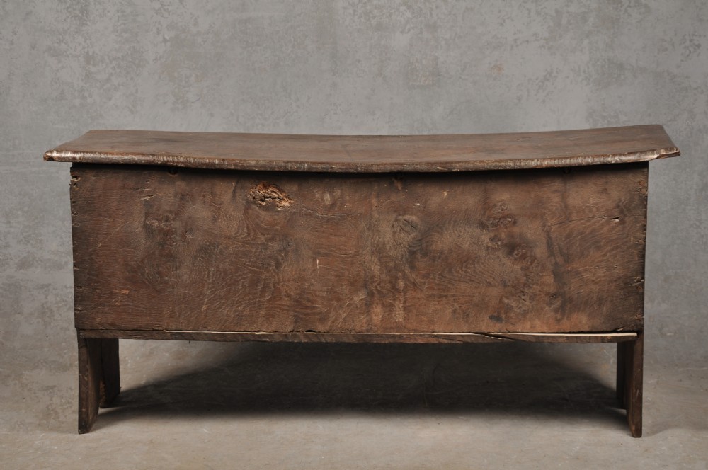 A low 17th-century dark oak coffer with relief carved lunette patterns and a central iron lockplate. View X