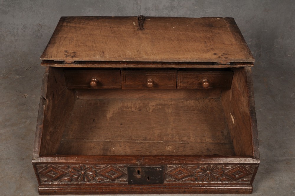 A seventeenth-century dark oak slant-front desk box with relief rosette carvings and iron hardware. View VI