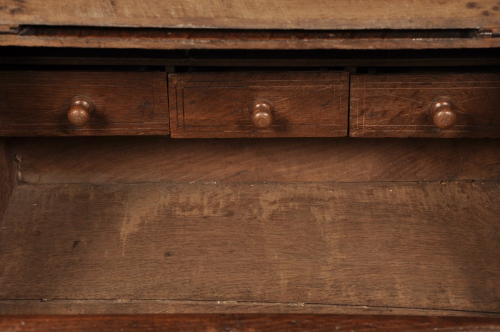 A seventeenth-century dark oak slant-front desk box with relief rosette carvings and iron hardware. View VII