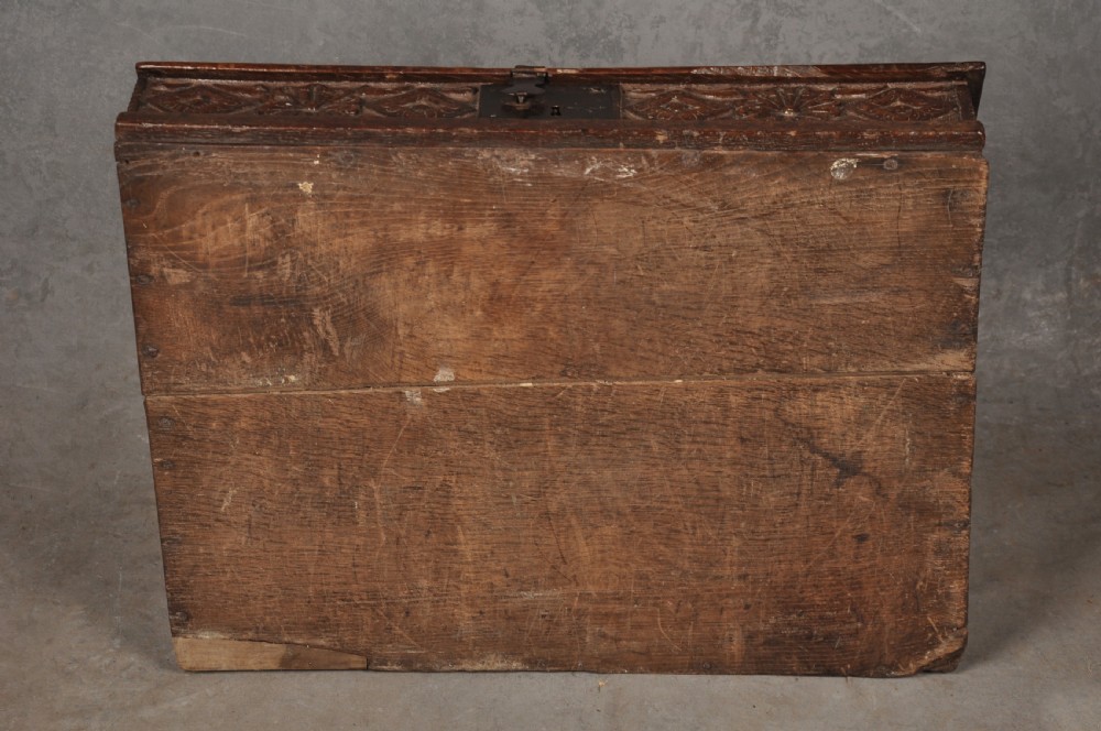 A seventeenth-century dark oak slant-front desk box with relief rosette carvings and iron hardware. View X