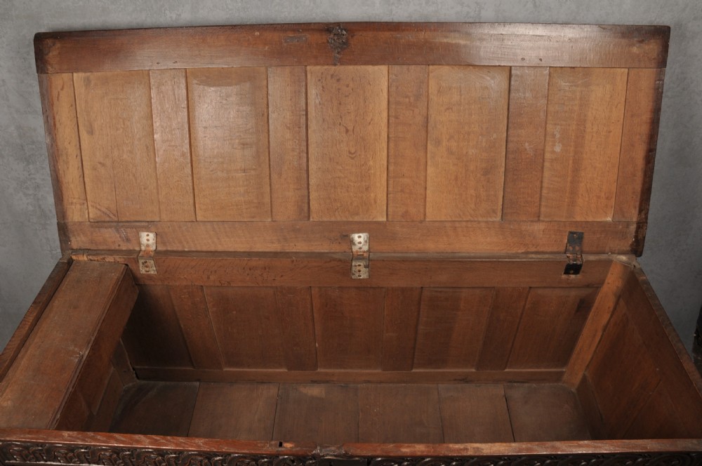 A large seventeenth-century dark oak coffer featuring five carved panels decorated with geometric lozenge and rosette motifs beneath a carved upper frieze. View V