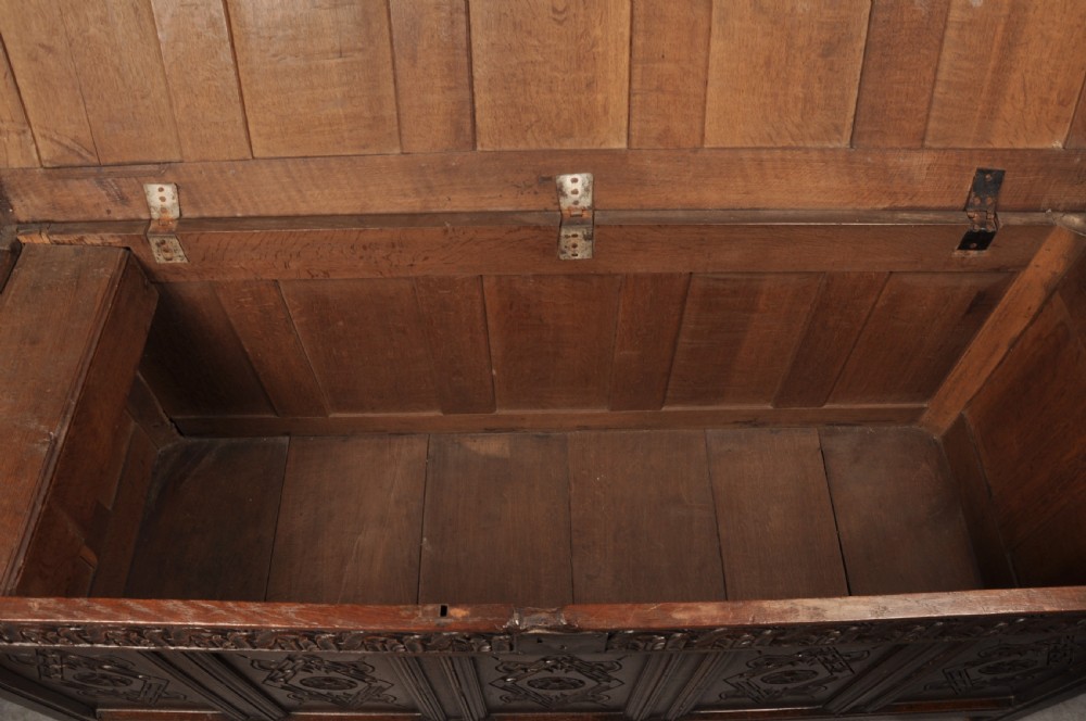 A large seventeenth-century dark oak coffer featuring five carved panels decorated with geometric lozenge and rosette motifs beneath a carved upper frieze. View VI
