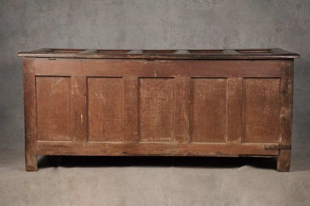 A large seventeenth-century dark oak coffer featuring five carved panels decorated with geometric lozenge and rosette motifs beneath a carved upper frieze. View XI