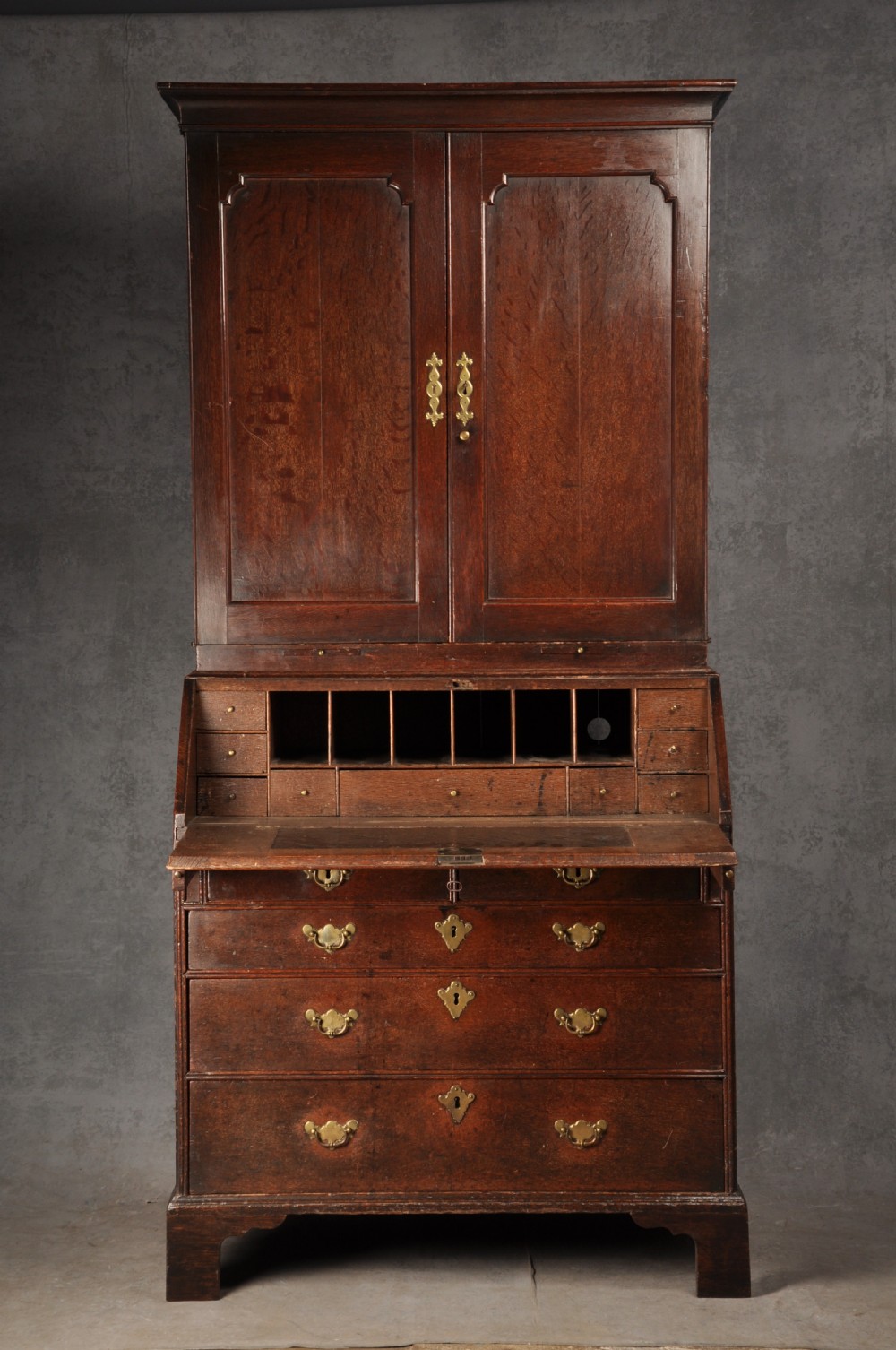 An early 18th-century dark oak bureau bookcase with a two-door upper section, a sloped writing fall, and long drawers on bracket feet. View III