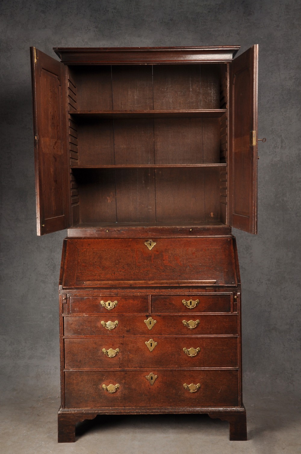 An early 18th-century dark oak bureau bookcase with a two-door upper section, a sloped writing fall, and long drawers on bracket feet. View IV