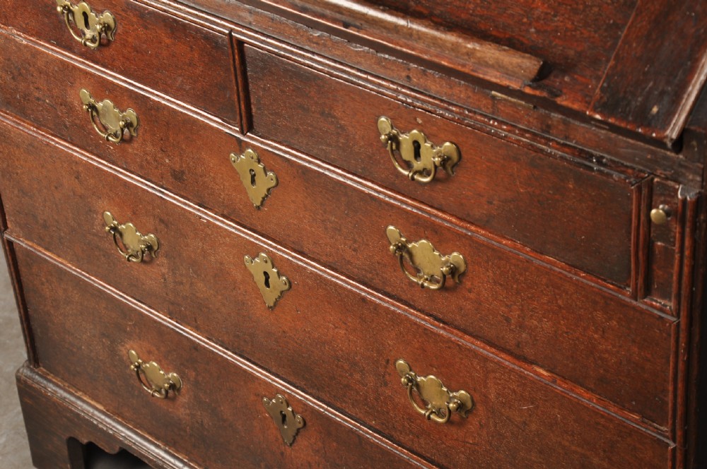 An early 18th-century dark oak bureau bookcase with a two-door upper section, a sloped writing fall, and long drawers on bracket feet. View XV