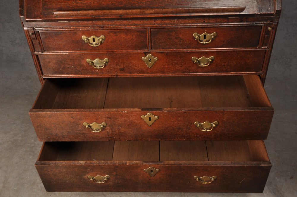 An early 18th-century dark oak bureau bookcase with a two-door upper section, a sloped writing fall, and long drawers on bracket feet. View XVI