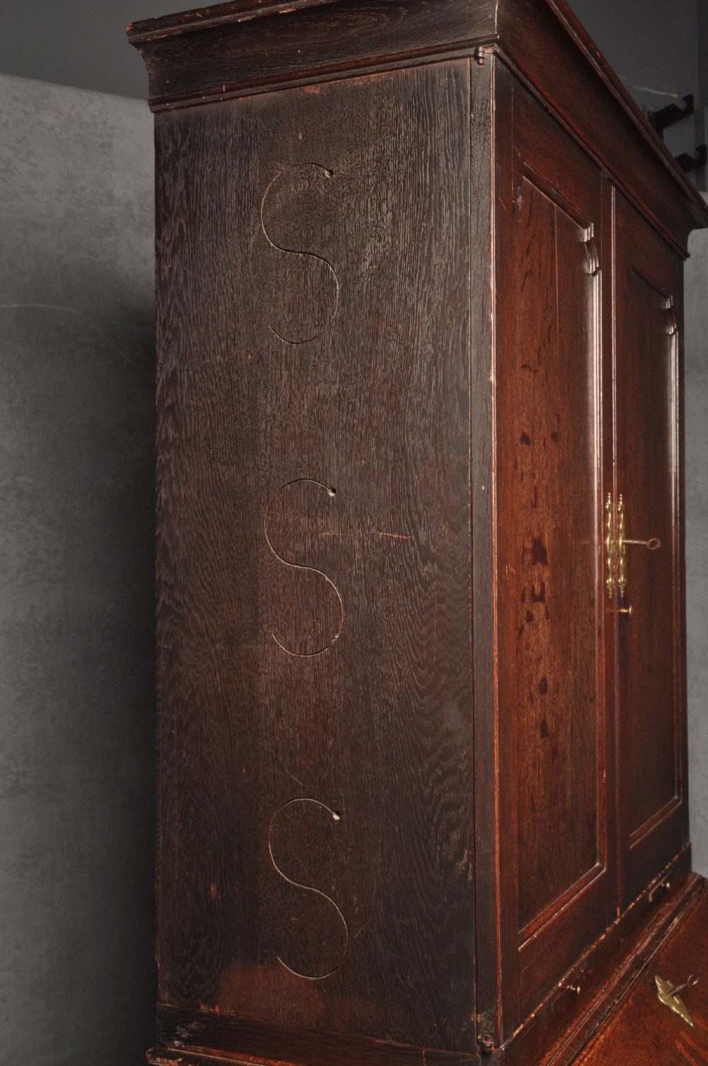 An early 18th-century dark oak bureau bookcase with a two-door upper section, a sloped writing fall, and long drawers on bracket feet. View XIX