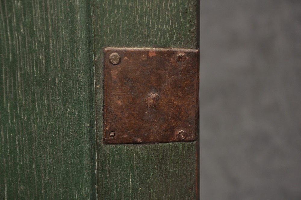 An early eighteenth-century dark oak bow-fronted corner cupboard featuring a curved fielded panel door, brass escutcheon, and moulded cornice. View V