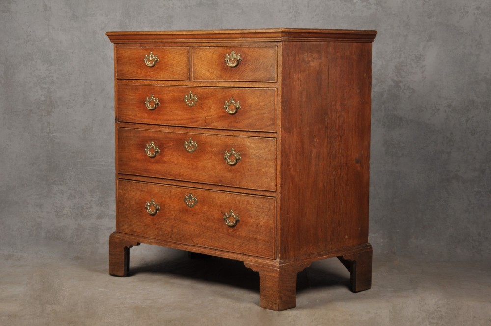 An 18th-century Georgian oak chest of drawers featuring two short drawers over three long drawers with brass drop handles and bracket feet. View II