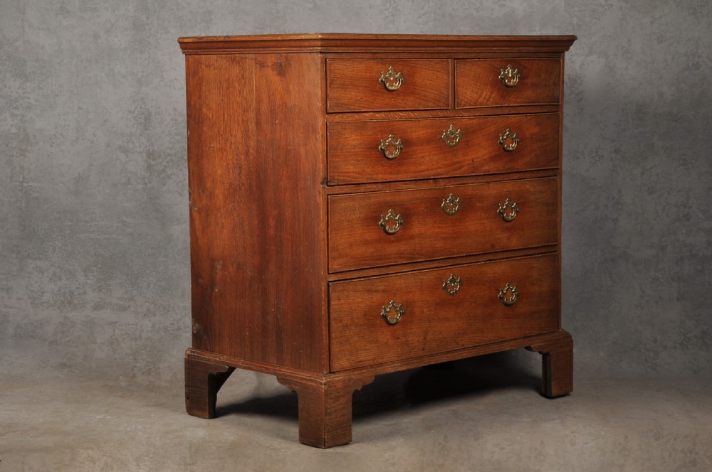 An 18th-century Georgian oak chest of drawers featuring two short drawers over three long drawers with brass drop handles and bracket feet. View III