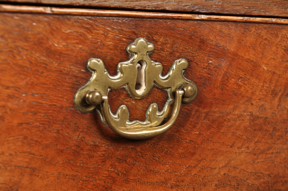 An 18th-century Georgian oak chest of drawers featuring two short drawers over three long drawers with brass drop handles and bracket feet. View IV